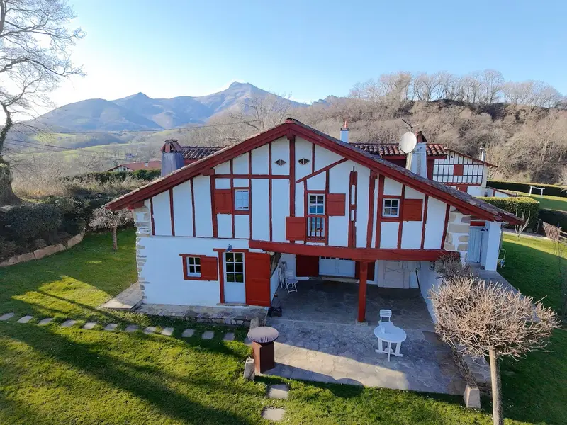 La maison Errotaldekoborda, façade à colombages rouges, avec La Rhune en arrière-plan